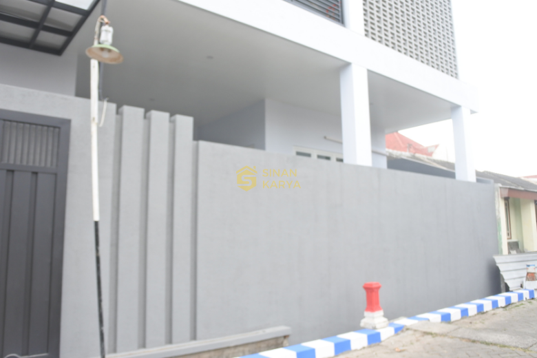 Pagar belakang tinggi dengan elemen dekoratif yang menjaga privasi sambil memungkinkan cahaya alami masuk